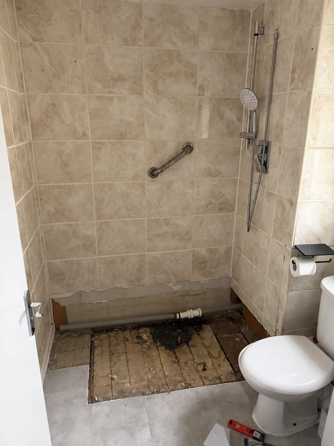 Bathroom in Basildon after the leaking shower tray was removed, exposing the floor and waste pipework